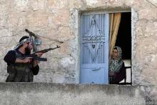 A member of the Free Syrian Army talks to a woman during a patrol to search for pro-government forces in Haram town, Idlib Governorate on October 26, 2012 