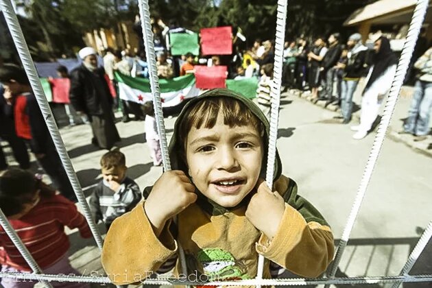 A Syrian refugee boy stands behind the fence during a protest against Syria's President Bashar al-Assad at Yayladagi refugee camp in Hatay province on the Turkish-Syrian border March 30, 2012