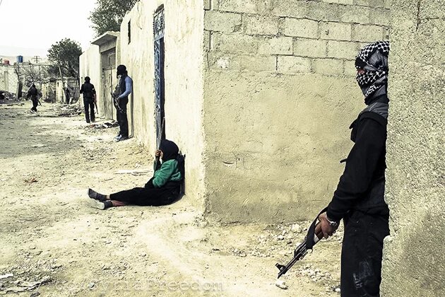 إمرأة سورية تجلس أمام منزلها بينما يتّخذ مقاتلوا الجيش الحرّ مواقع دفاعية خلال فترة وقف إطلاق النار في أحد أحياء دمشق. 1نيسان/أبريل 2012